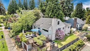 A residential house with a deck, surrounded by lush greenery and trees. - 4bd w/ Lake Views and Chef's Kitchen (Seattle)
