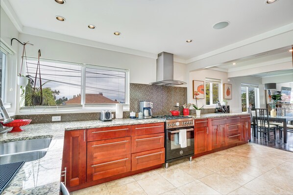 A spacious kitchen with granite countertops, wooden cabinets, and a large island. - 4bd w/ Lake Views and Chef's Kitchen (Seattle)