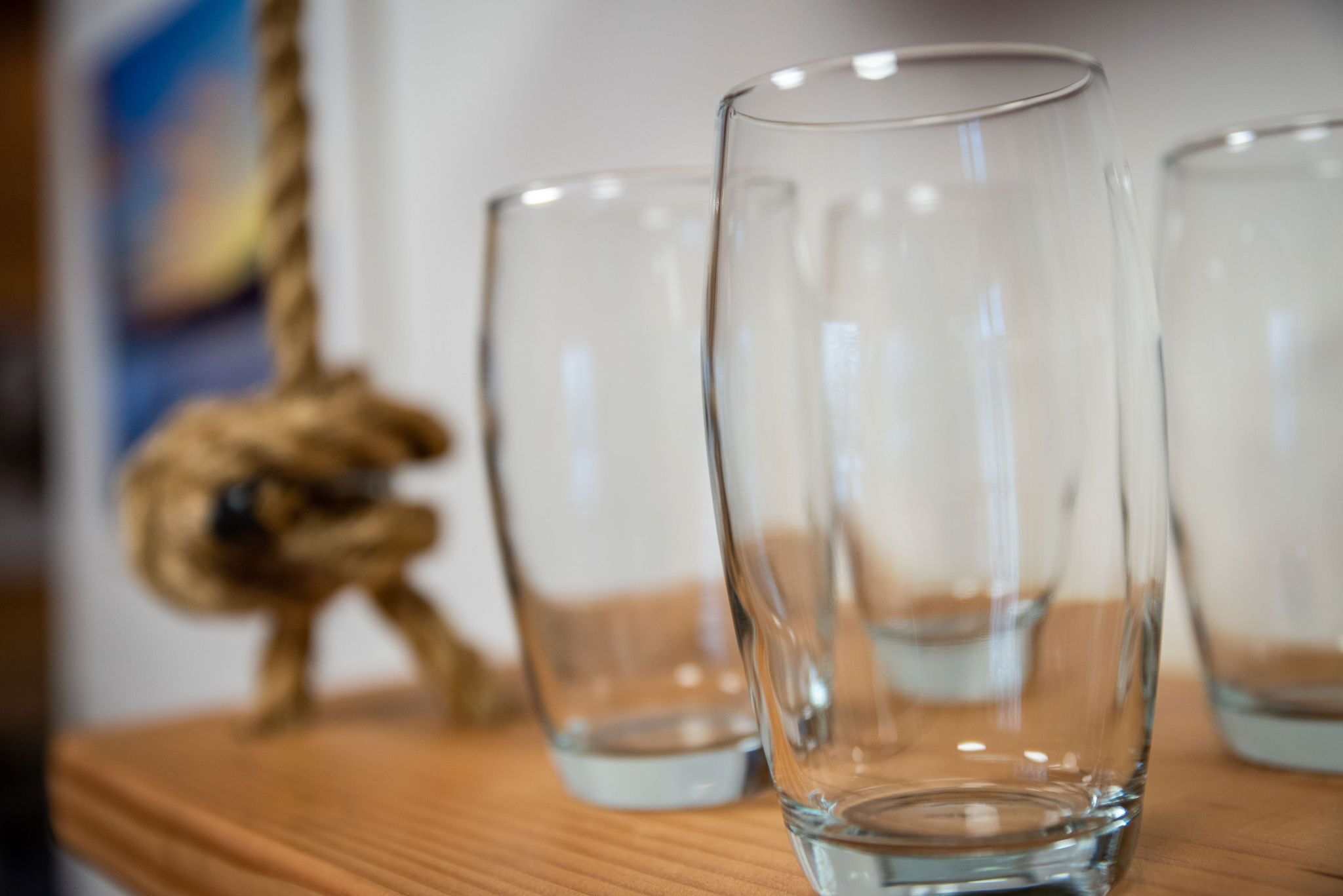 Une surface en bois sur laquelle reposent trois verres transparents et une petite figurine.