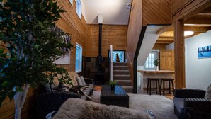 A cozy interior with wooden walls, a staircase, a dining area, and a living room with furniture.