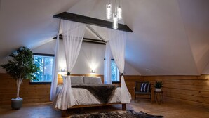 A bedroom with a canopy bed, wooden walls, a large window, a potted plant, and a fur rug.