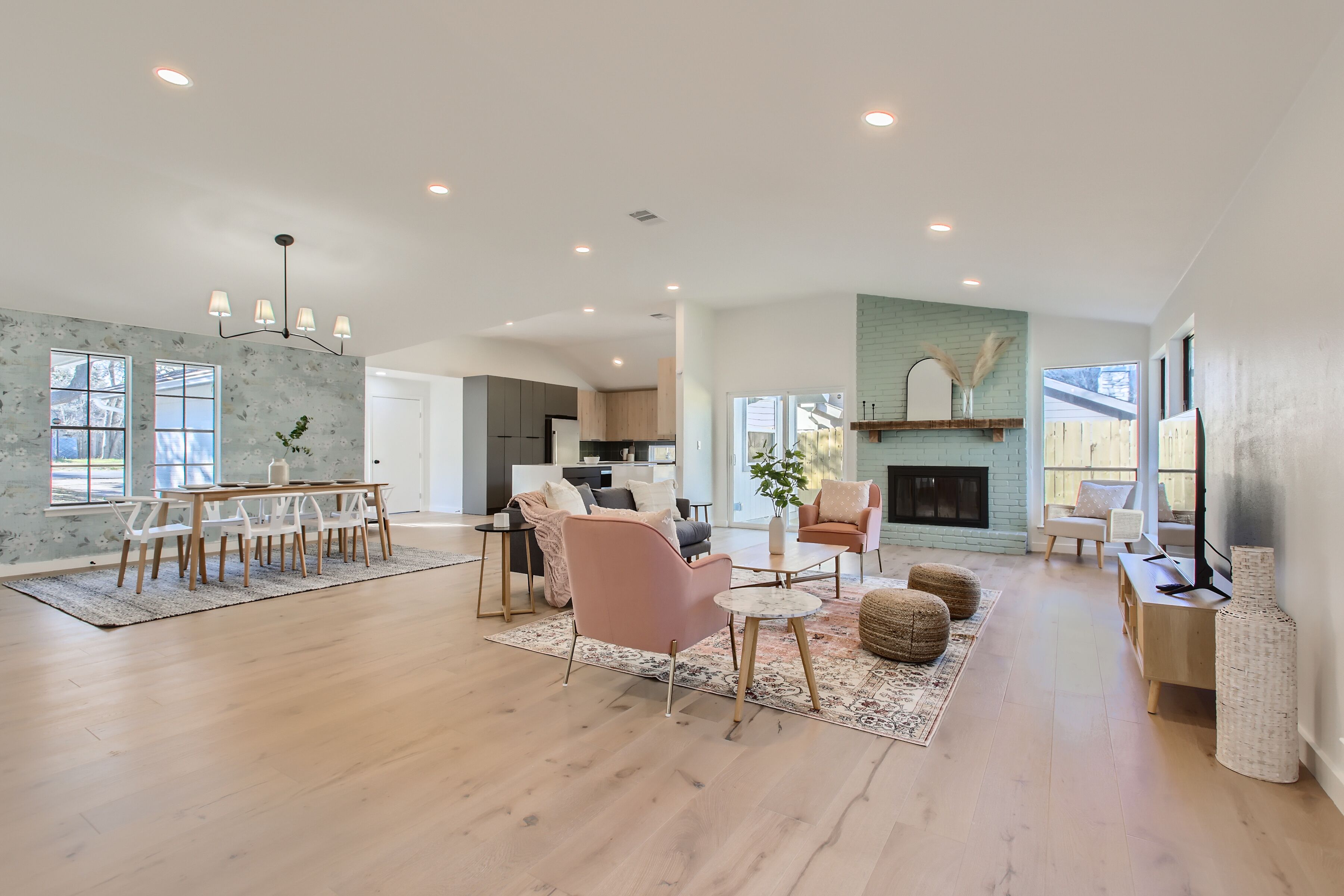A spacious living room with a dining area, a fireplace, and a kitchen in the background.