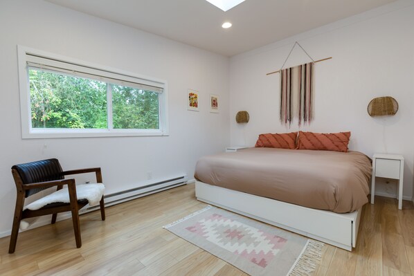 Une chambre à coucher comprenant un lit, une chaise, une fenêtre et un élément décoratif fixé au mur.