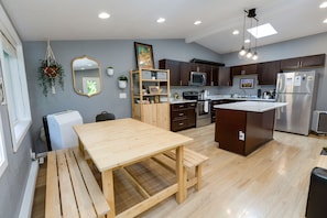 Una cocina moderna con armarios de madera, una isla central y un comedor con mesa y banco de madera.