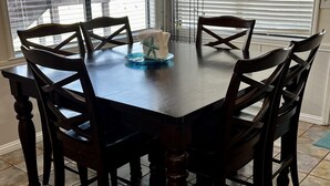 Een eettafel met zes stoelen, een blauw glazen bord en een witte servettenhouder met een sterdessin.