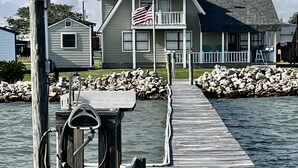 Een houten steiger die leidt naar een huis met een balkon en een Amerikaanse vlag.