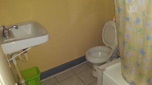 A small bathroom with a toilet, a sink, and a shower curtain. - Royal Savanna Inn Hotel (Savanna la Mar)