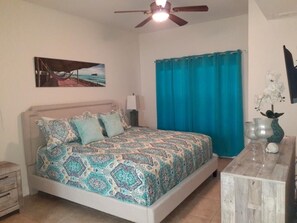 Cozy retreat with a single bed, ceiling fan, and a beautiful beach scene painting.