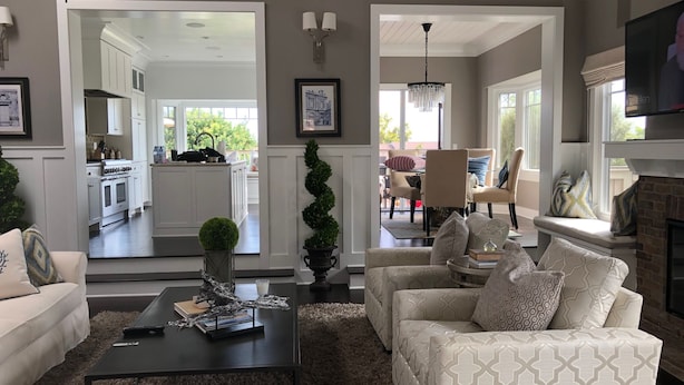 A living room with a sofa, coffee table, and fireplace. There is a kitchen visible through an open doorway.