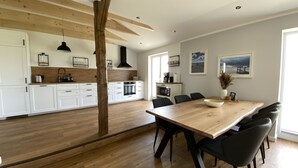 Une cuisine moderne avec des meubles blancs, une table à manger en bois et des chaises noires.