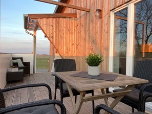 Eine Holzterrasse mit Tisch und Stühlen, einem Blumentopf und Blick auf die Landschaft.
