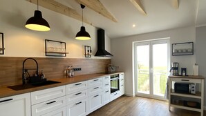 Une cuisine moderne avec des meubles en bois, un évier noir et des luminaires suspendus.