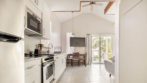 A kitchen with a built-in oven, microwave, and gas stove. There is a dining table with chairs and a TV mounted on the wall. - Paradise on the Bay  (Goodland)