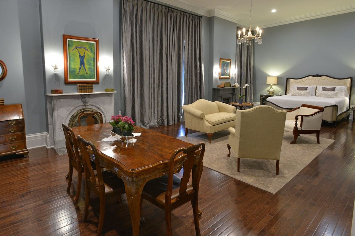 A room with a wooden dining table, a sofa, a bed, and a fireplace.