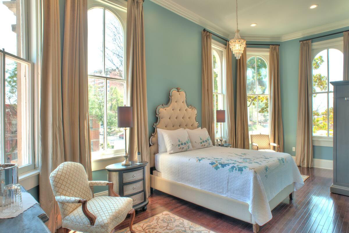 A bedroom with a large bed, a chair, a nightstand, and a dresser.