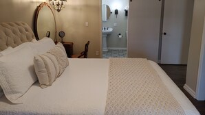 Ein Schlafzimmer mit einem großen Bett, einem Nachttisch mit Lampe, einem Sessel und einem Kleiderschrank.