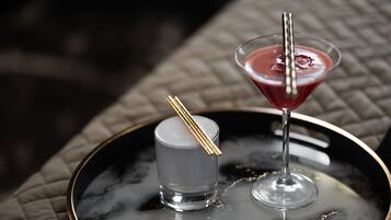 Two drinks on a tray, one in a martini glass and one in a shot glass, with a gold-colored spoon resting on the shot glass.