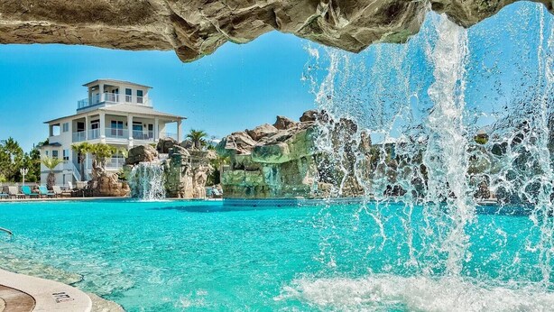 Uma piscina com água turquesa cristalina, rodeada por formações rochosas e uma cascata.