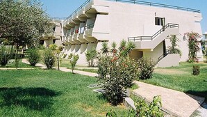 A modern building with multiple balconies and a well-maintained garden area. - Virginia Apartments (Rhodes)