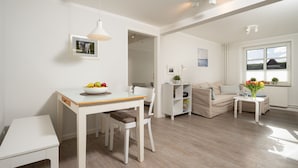 Een moderne woonkamer met een eettafel, een bank en een bijzettafeltje met een vaas.
