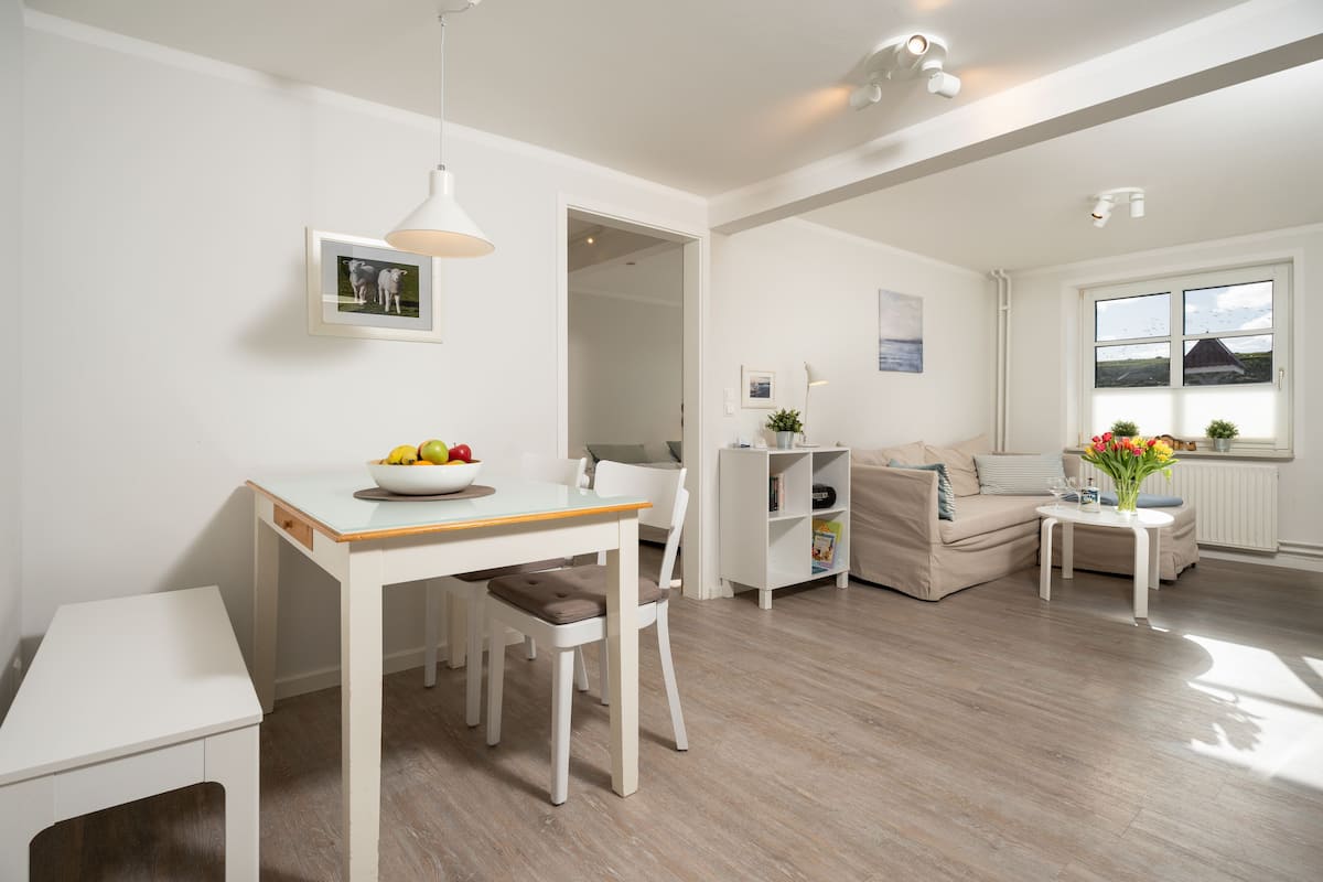 Een moderne woonkamer met een eettafel, een bank en een bijzettafeltje met een vaas.