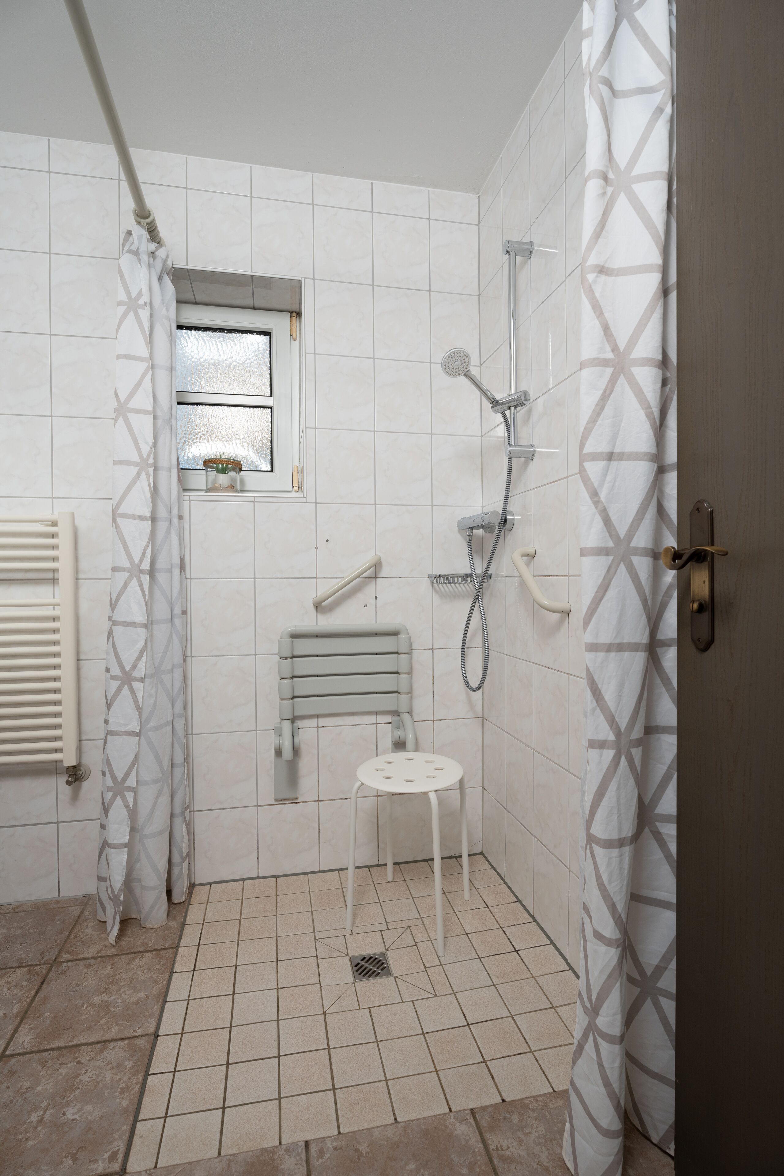 Ein kleines Badezimmer mit Dusche, Toilette und Fenster.