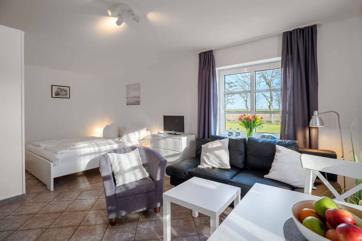 Een moderne hotelkamer met een bed, een bank, een salontafel en een televisie.