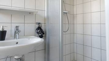 A bathroom with a white sink, mirror, and shower.