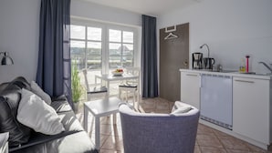 Een moderne woonkamer met een bank, een eettafel en een keukenhoek met een spoelbak en koffiezetapparaat.