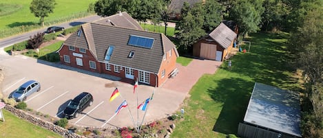 An aerial view of a building with a parking lot, a small garden, and flags.