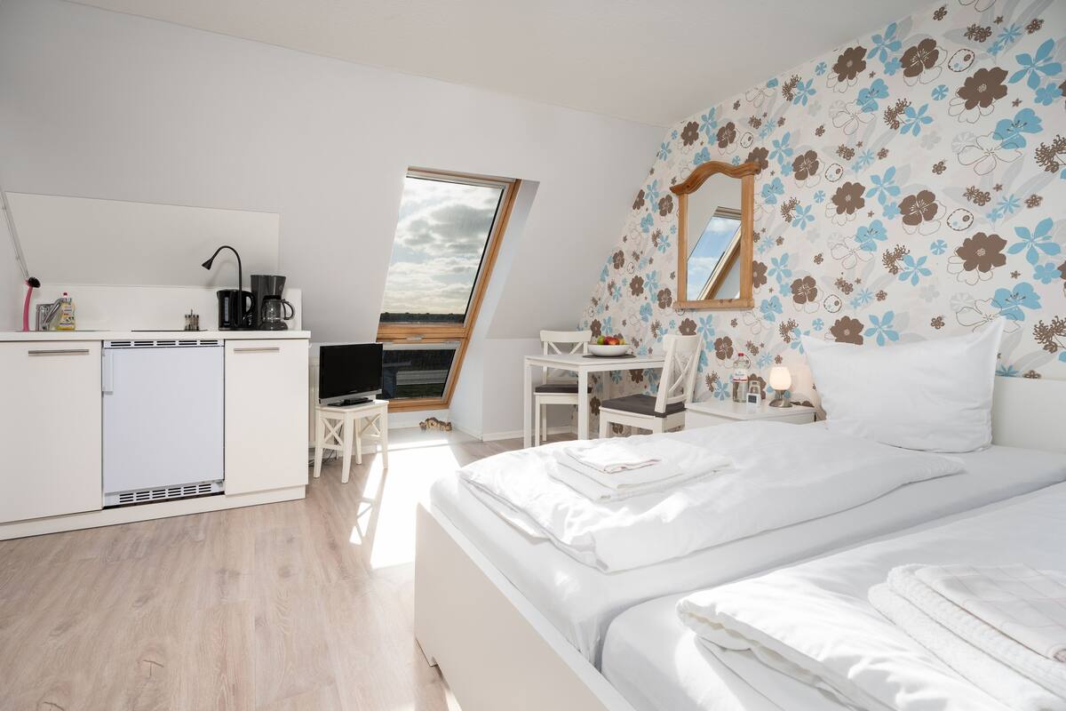 Een moderne slaapkamer met een groot bed, een bureau en een kitchenette.