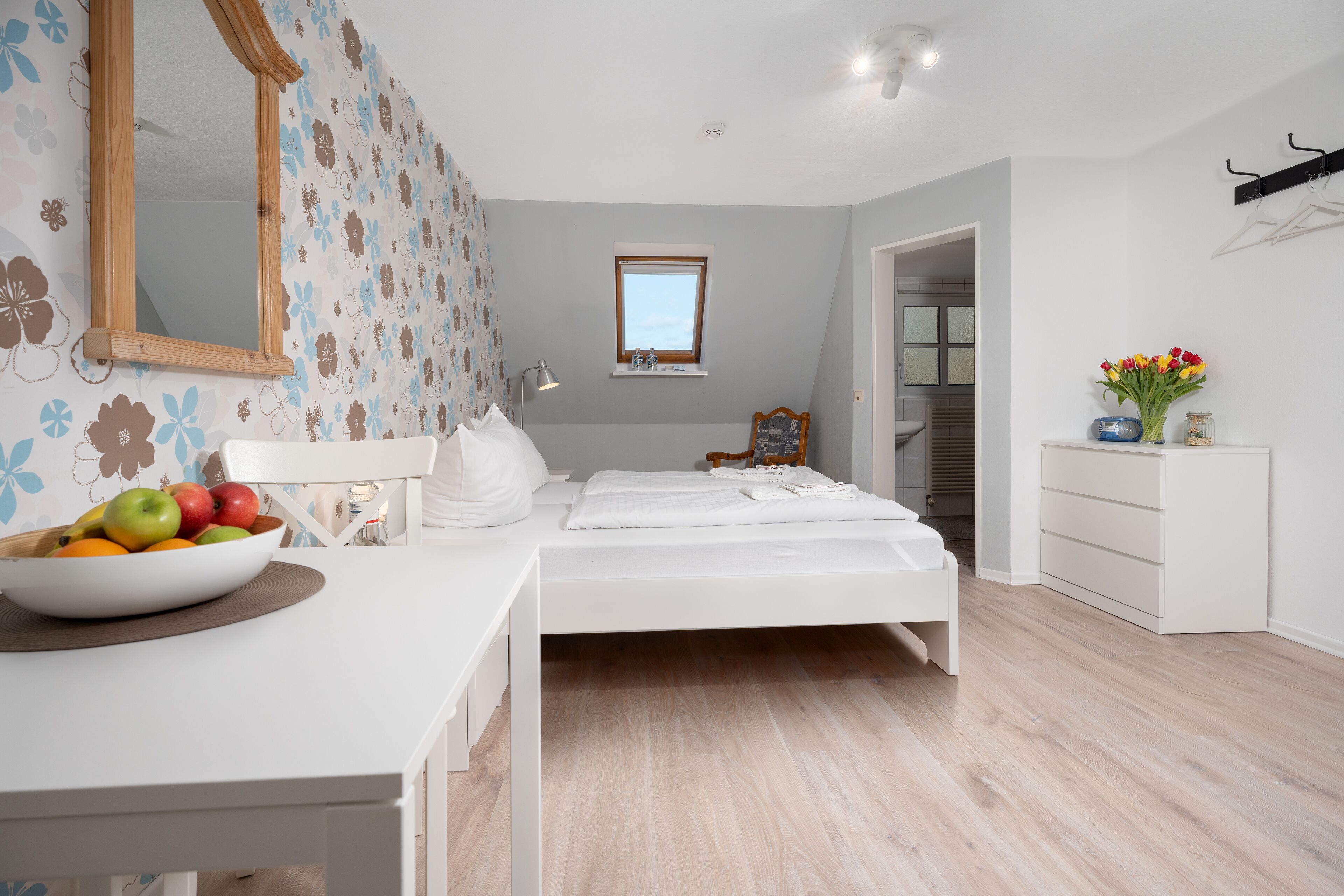 Een moderne slaapkamer met een bed, nachtkastje en een schaal fruit.