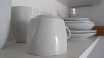 Une étagère blanche sur laquelle sont disposés divers objets en céramique blanche, notamment des tasses et des assiettes.