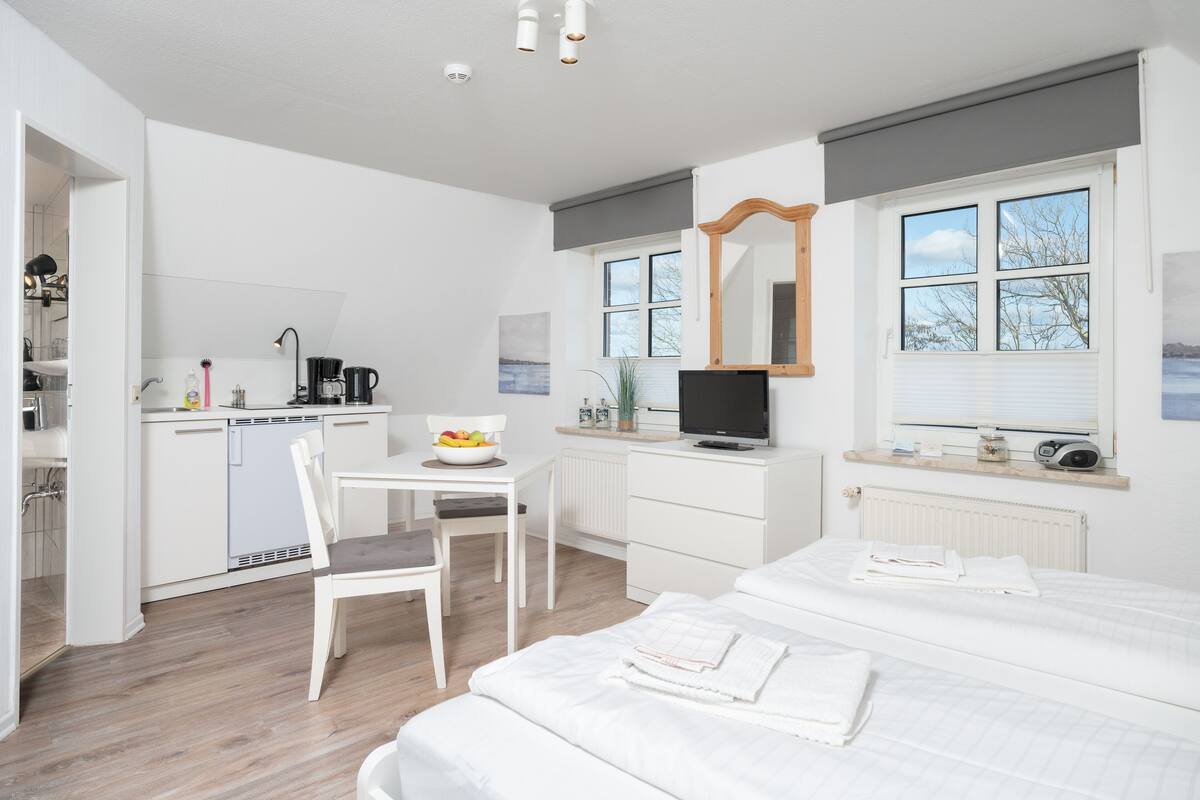 Een moderne hotelkamer met een kitchenette, een eethoek, een televisie en een groot raam met uitzicht.