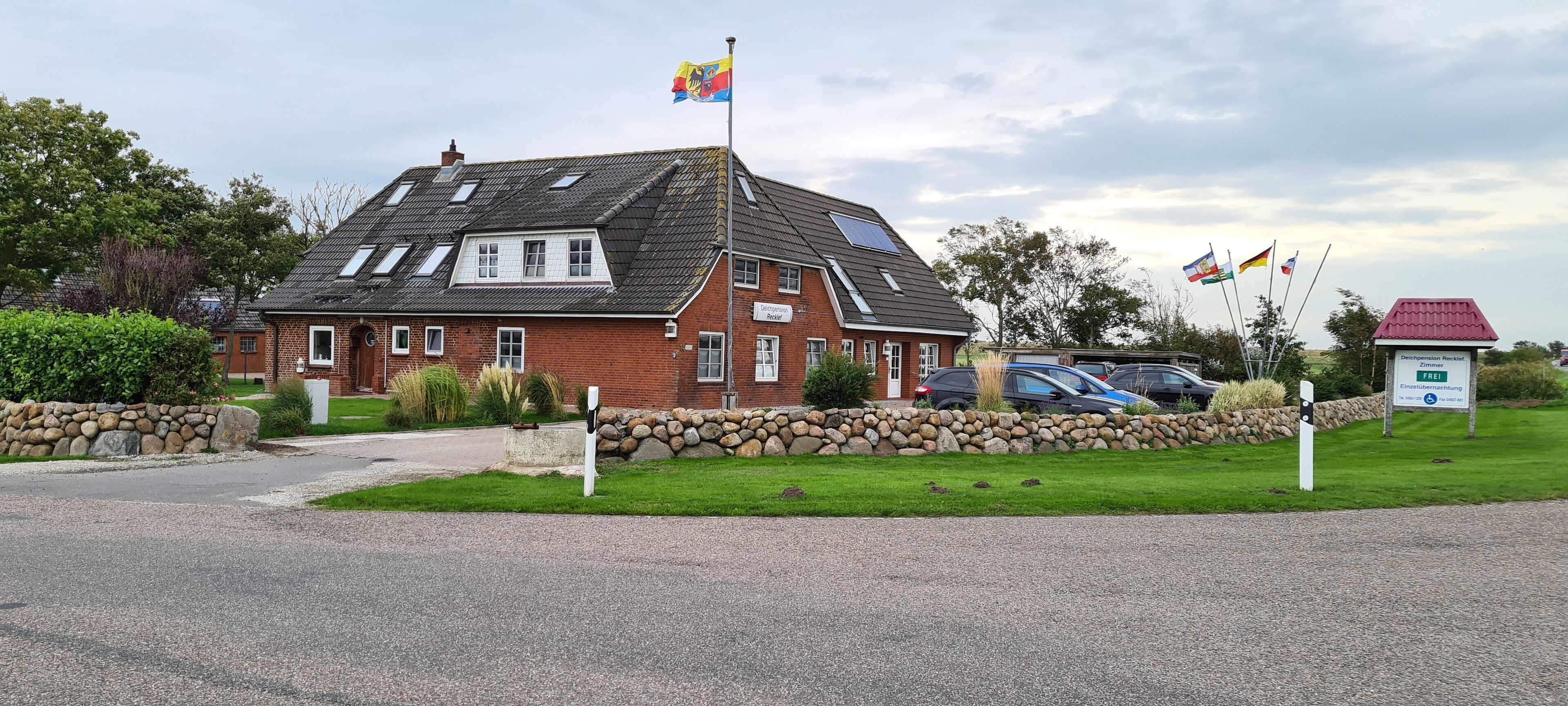 A brick building with a sloped roof, solar panels, and multiple flags.