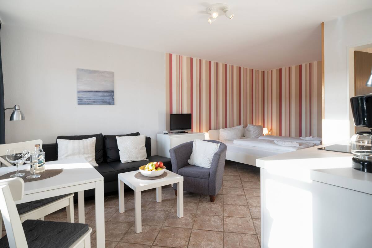 Een moderne hotelkamer met een bank, een eettafel, een fauteuil, een bed en een televisie.
