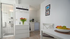 Een moderne keuken met witte kastjes, een spoelbak en een eethoek met een schaal fruit.