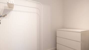 A room with a white wardrobe, a black mat at the entrance, and a ceiling light fixture.