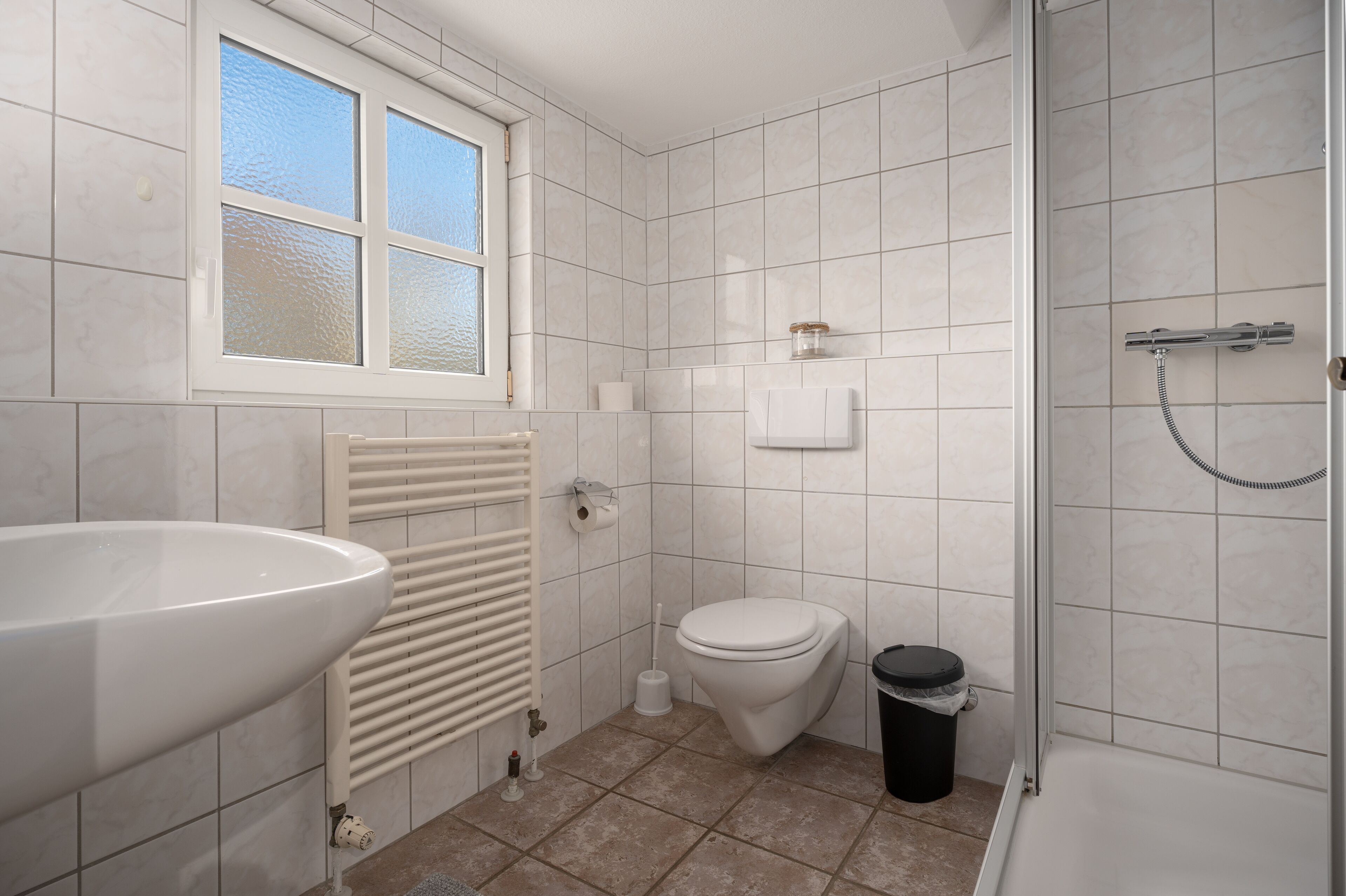 A bathroom with a large sink, toilet, and shower.
