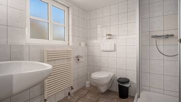 A bathroom with a large sink, toilet, and shower.