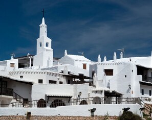 Un edificio blanco con un campanario, rodeado de estructuras blancas similares.