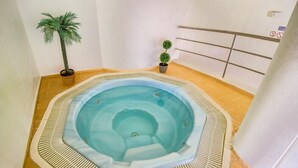 A hot tub in a corner of a room with tiled flooring, a palm tree, and a small potted plant. - Borda D Agua Apartments (Albufeira)