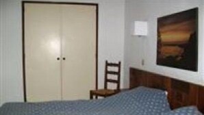 A bedroom with a bed, a chair, a wardrobe, and a painting on the wall. - Borda D Agua Apartments (Albufeira)