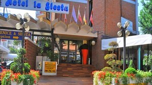 A hotel entrance with a sign reading "Hotel la Siesta," a brick facade, and steps leading up to the entrance. - La Fenice (Jesolo)