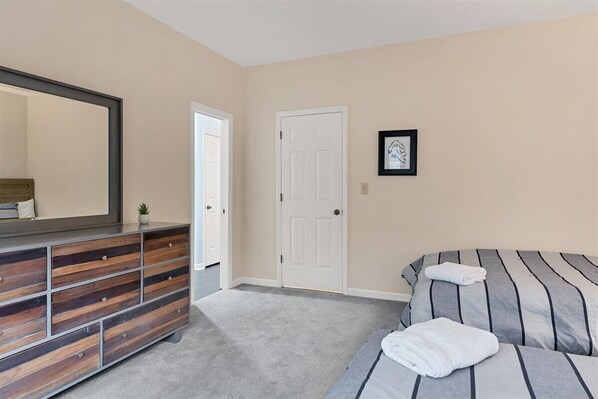 A bedroom with a bed, a dresser, a door, and a framed picture on the wall.