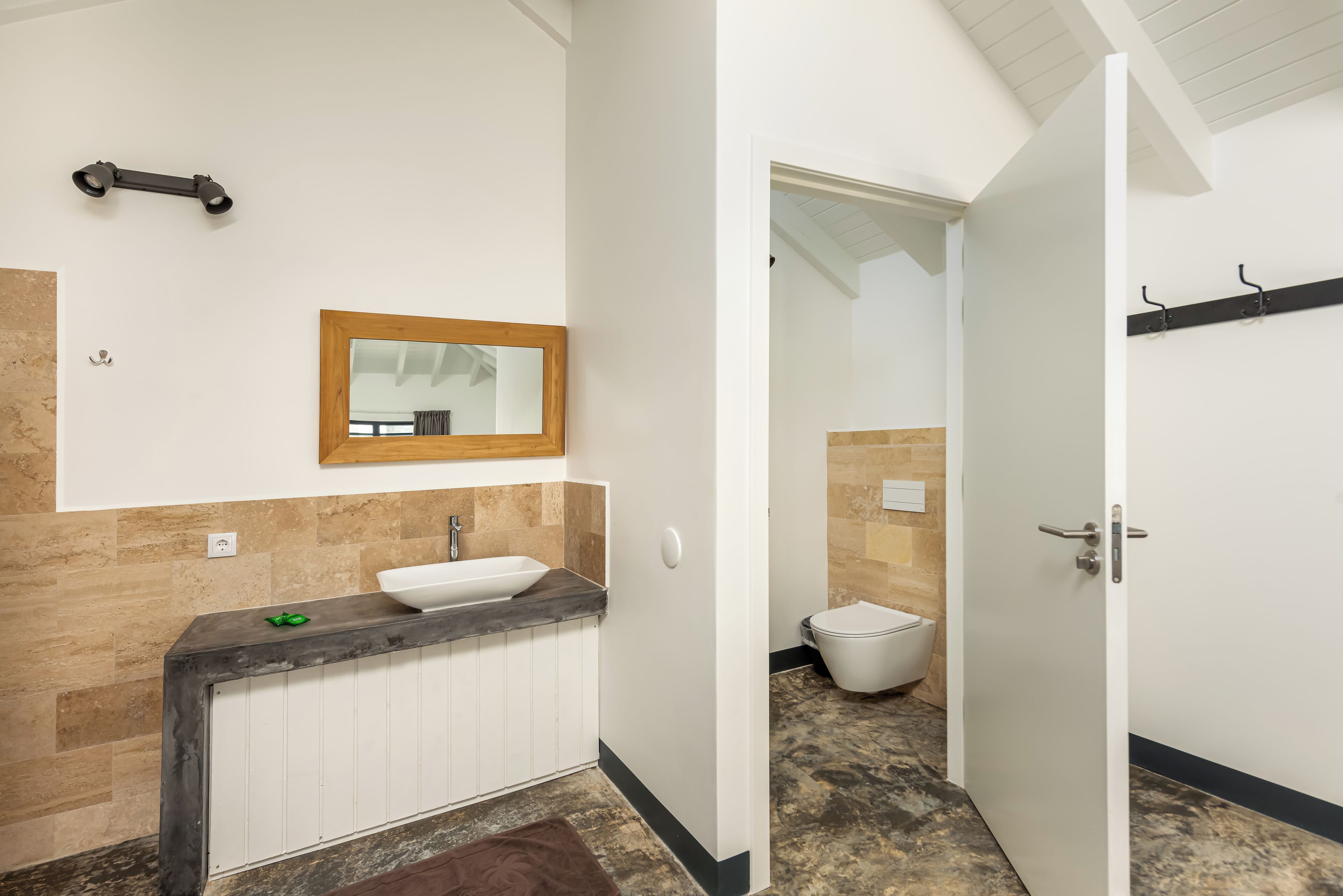 A modern bathroom with a white sink, a wooden-framed mirror, and a toilet.