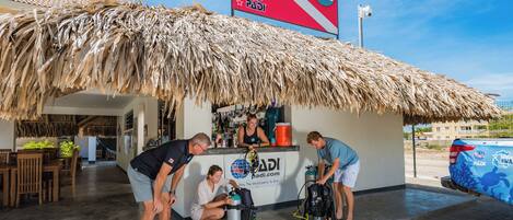 A thatched-roof structure with a PADI logo, a sign, and a water bottle.
