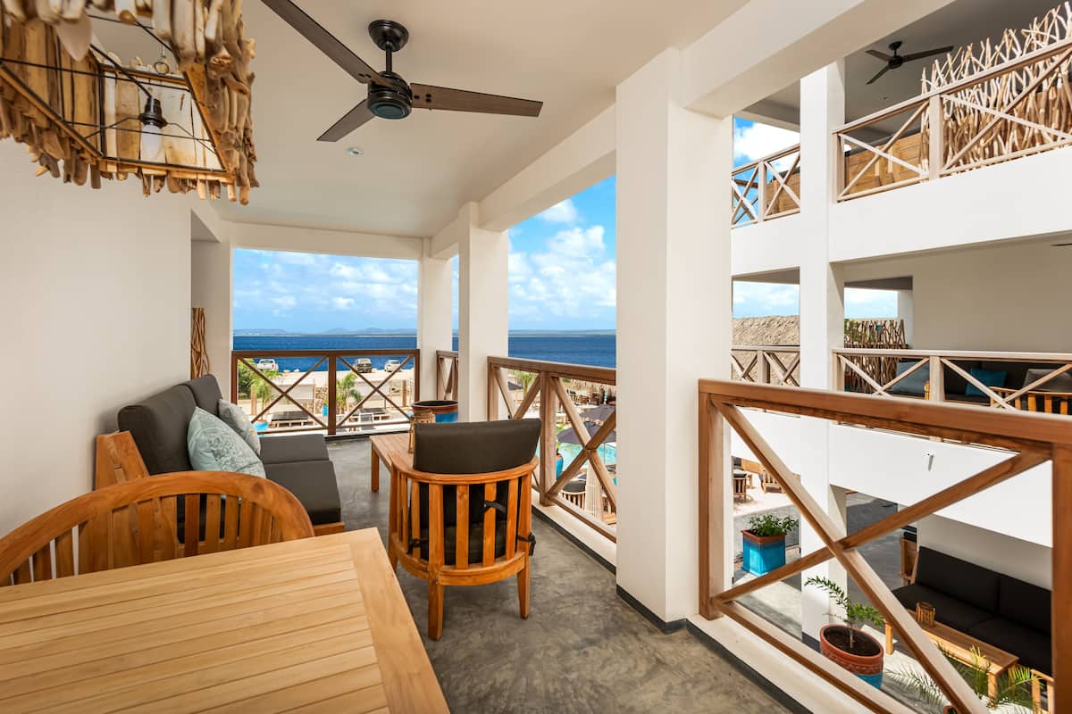 A balcony with wooden furniture, a ceiling fan, and a view of the ocean.
