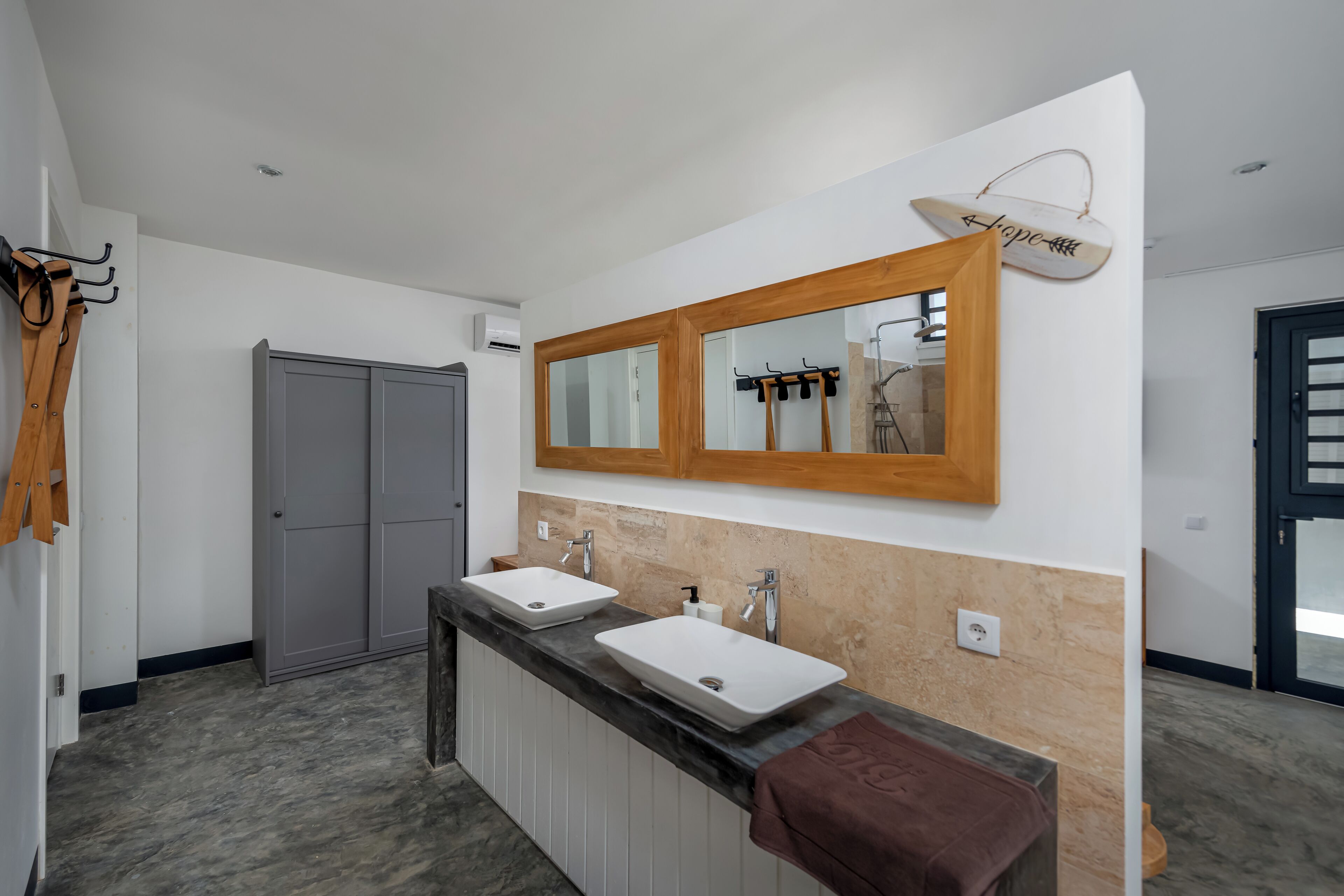 A modern bathroom with two sinks, a large mirror, and a towel rack.