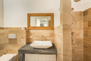 A bathroom with a white sink, a wooden-framed mirror, and a shower area. - Bloozz resort Bonaire (Kralendijk)
